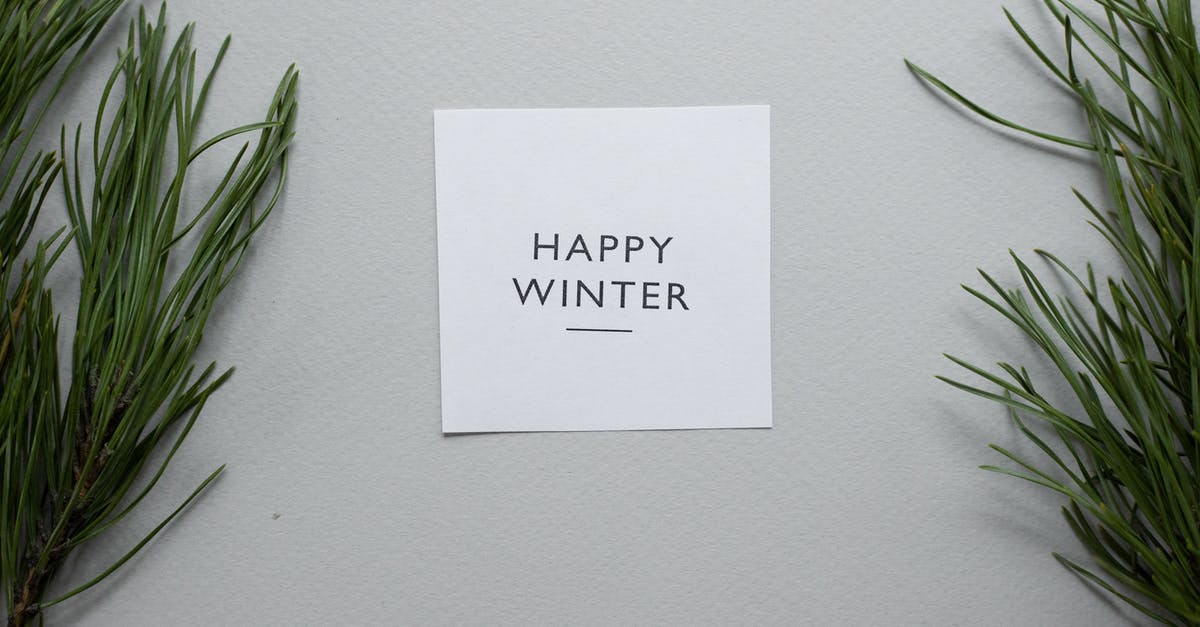 10-year Chinese Visa for Green Card Holder? - Top view of Happy Winter inscription written on white card placed on gray background with green coniferous twigs in studio