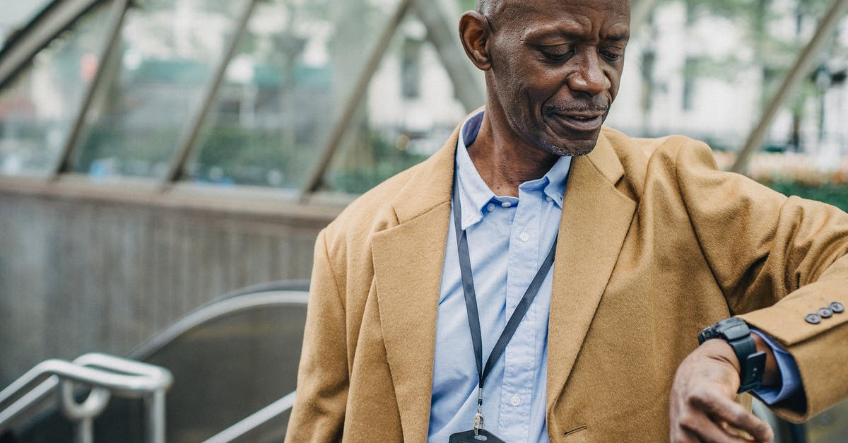 19 hour overnight layover in Dublin. Will the baggage be checked through? - Crop punctual African American male in elegant formal clothes standing near metro entrance and checking time on wristwatch