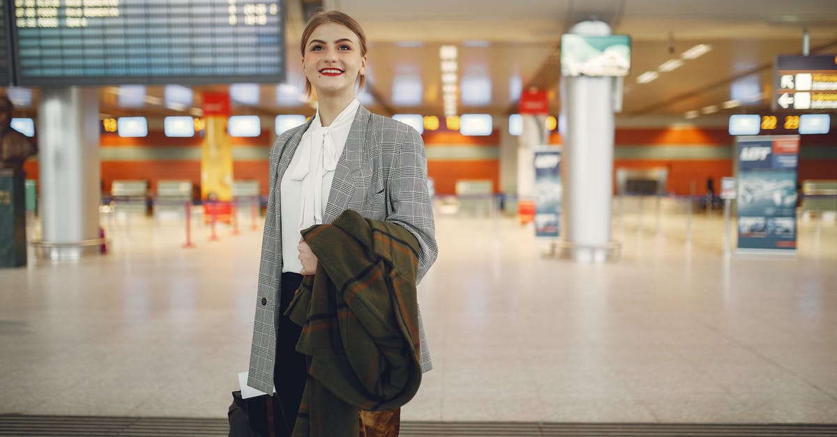 A day at Dubai International Airport and the city? - Back view of trendy businesswoman carrying baggage before flight near airport building A day at Dubai International Airport and the city? - Back view of trendy businesswoman carrying baggage before flight near airport building