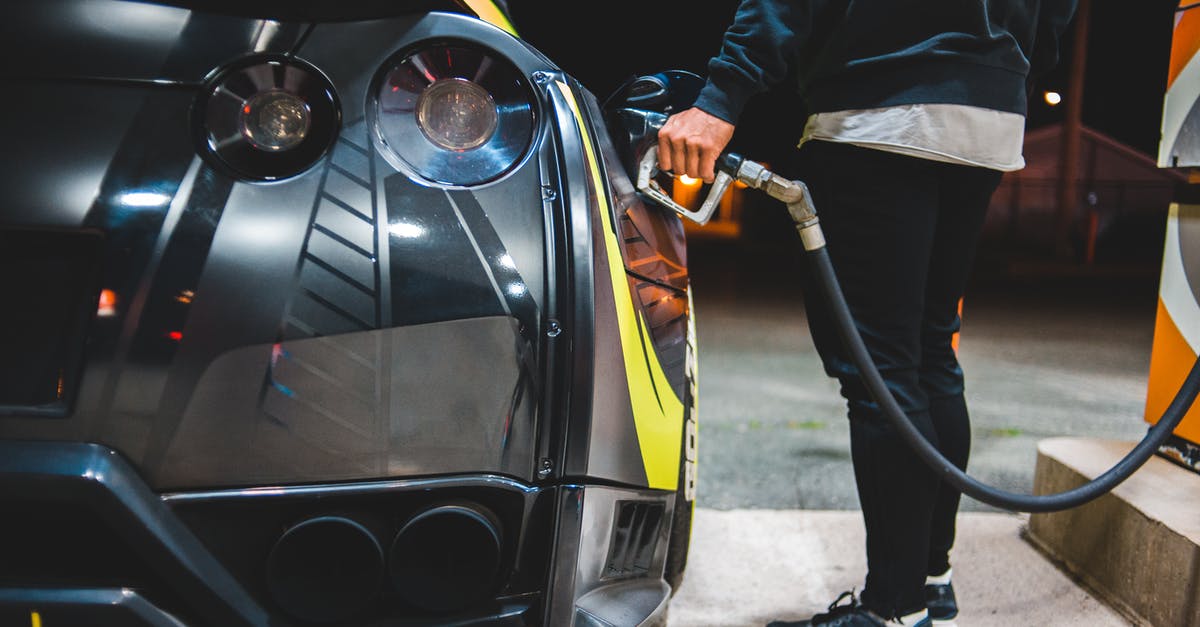 A stranger in US asks for a little of fuel at a gas station - Side view of crop unrecognizable male refueling modern racing automobile in petrol station in evening