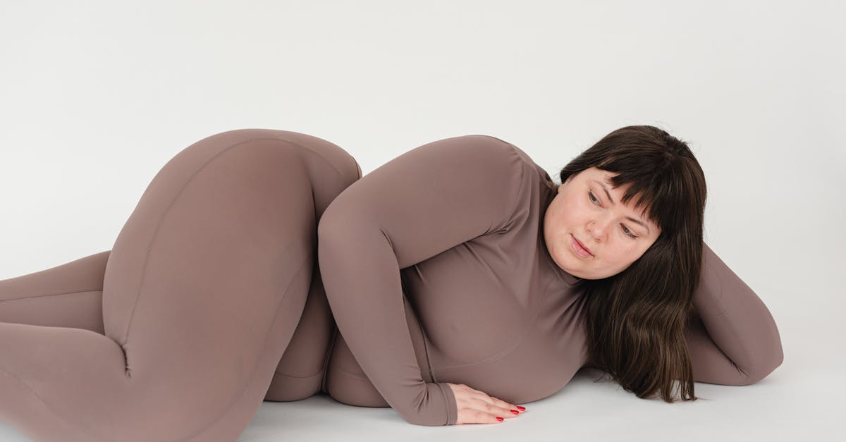 Acceptance of large bills in Denmark - High angle of serious plus size female with long hair leaning on hand while lying against white background Acceptance of large bills in Denmark - High angle of serious plus size female with long hair leaning on hand while lying against white background