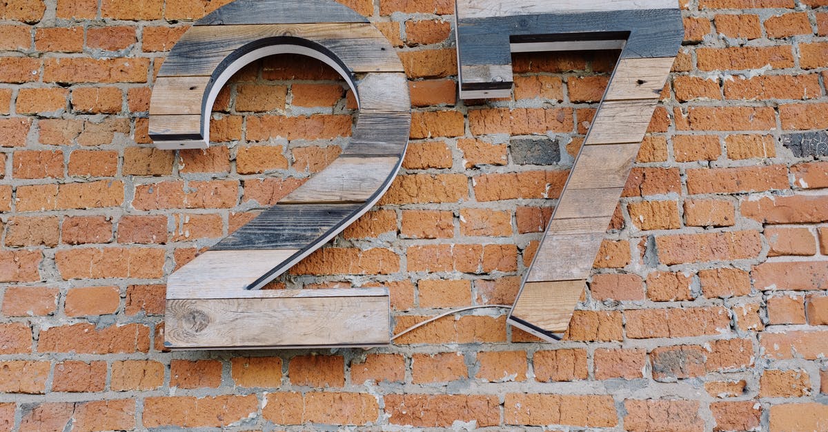 actual address is Different from the billing address on my ticket - Big wooden number sign hanging on brick wall of modern building actual address is Different from the billing address on my ticket - Big wooden number sign hanging on brick wall of modern building