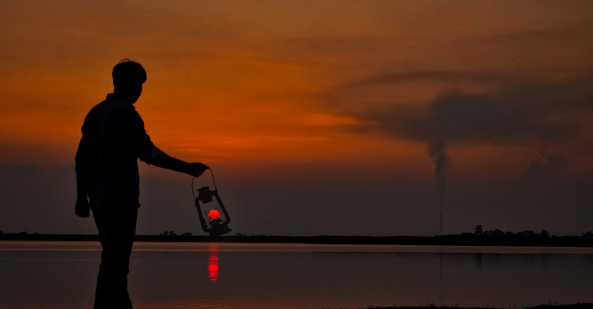 Air-side walk-through light boxes. What are they? - Silhouette of man with oil lamp on shore at sunset Air-side walk-through light boxes. What are they? - Silhouette of man with oil lamp on shore at sunset