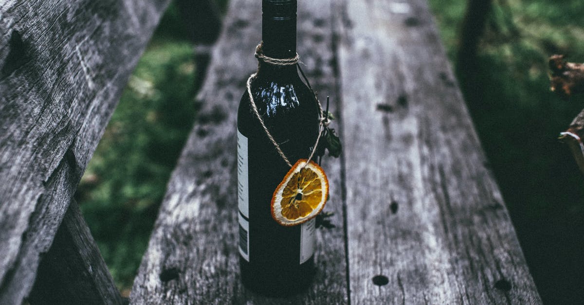 Alcohol as necessary medicine when visiting dry countries? - From above of glass bottle of wine with dried orange placed on old wooden bench in nature in daytime Alcohol as necessary medicine when visiting dry countries? - From above of glass bottle of wine with dried orange placed on old wooden bench in nature in daytime