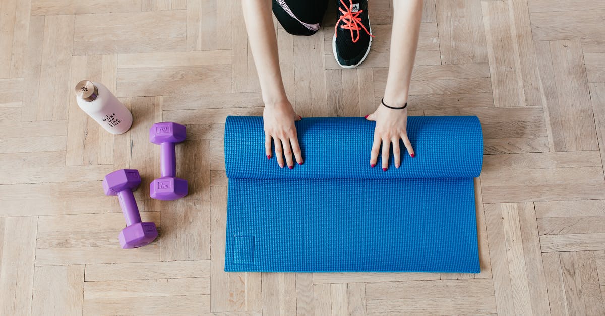 Alitalia hand baggage allowance in practice - Top view of anonymous female athlete in black leggings and sneakers unfolding blue mat for exercising on floor near dumbbells and water bottle in modern fitness center Alitalia hand baggage allowance in practice - Top view of anonymous female athlete in black leggings and sneakers unfolding blue mat for exercising on floor near dumbbells and water bottle in modern fitness center
