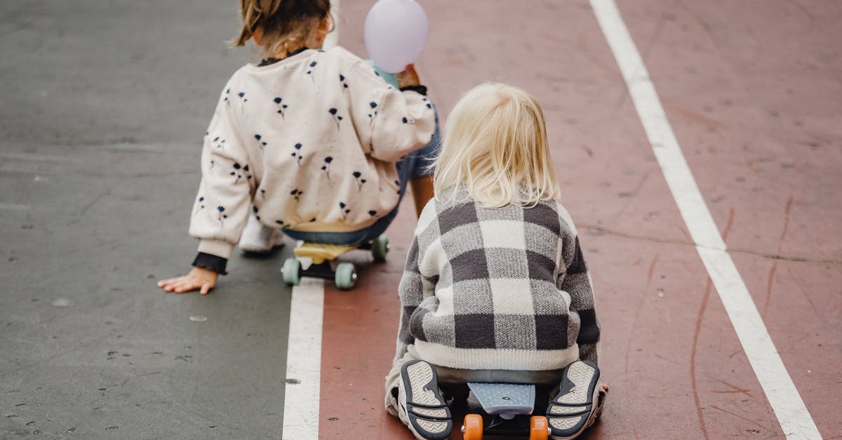 All day vs street parking in Edinburgh and Glasgow - Faceless children sitting on skateboards on asphalt road All day vs street parking in Edinburgh and Glasgow - Faceless children sitting on skateboards on asphalt road