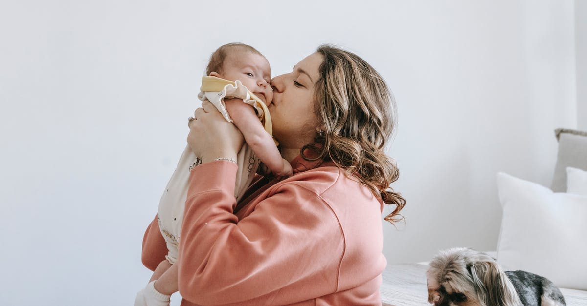 Am I able to carry on a small Swiss army knife? - Side view of happy woman kiss cute little baby while in bright room with puppy sitting on bed and Am I able to carry on a small Swiss army knife? - Side view of happy woman kiss cute little baby while in bright room with puppy sitting on bed and