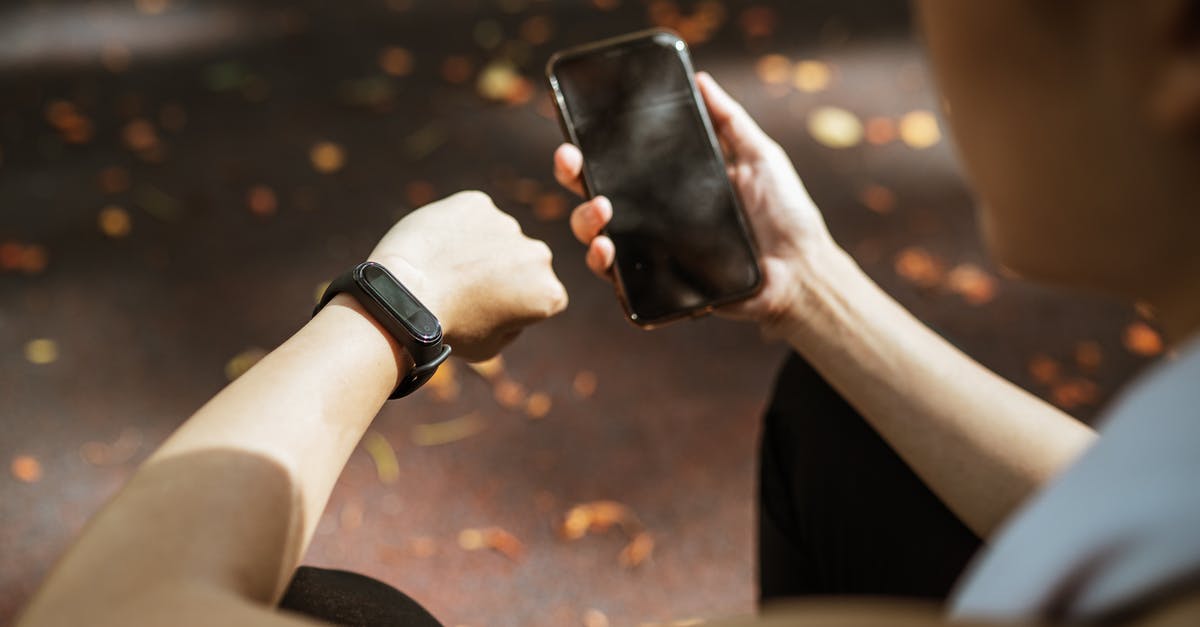 Am I allowed to take a monitor and a Slim PS2 to the UK? - Back view of anonymous female using smartphone app and smart watch after jogging in park