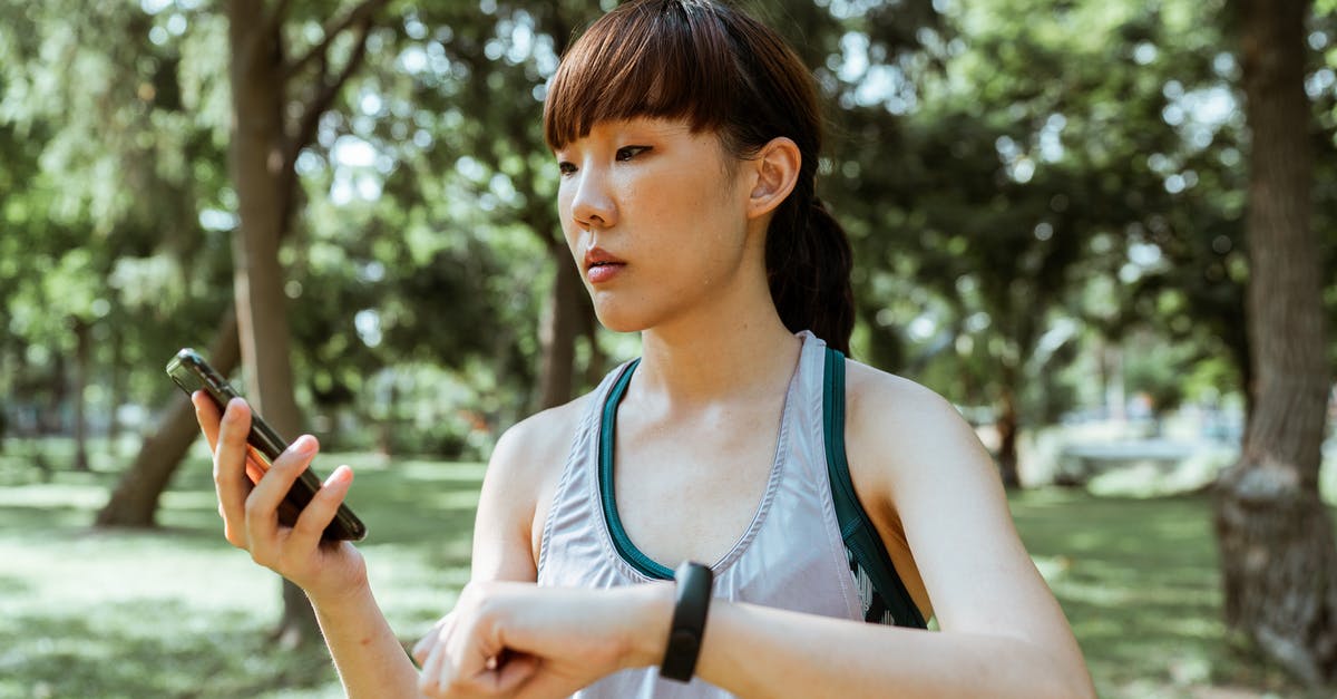 Am I allowed to take a monitor and a Slim PS2 to the UK? - Concentrated young Asian woman using smartphone in park