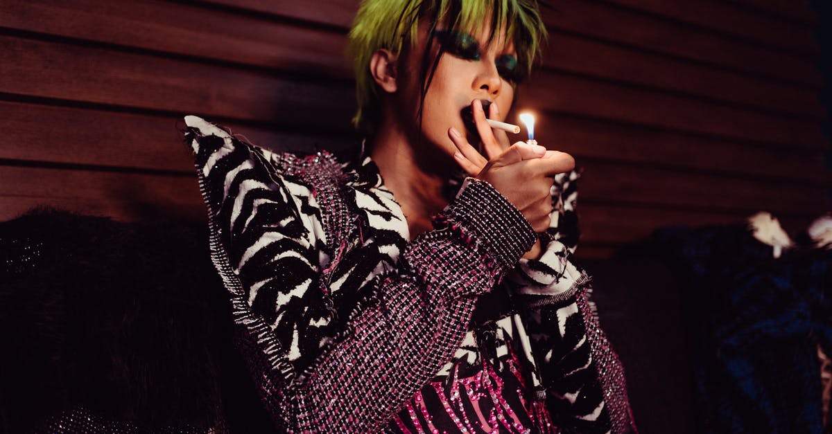 Am I likely to get problems travelling abroad from the UK when my gender appearance doesn't match my passport - Thoughtful transgender model in stylish outfit smoking cigarette