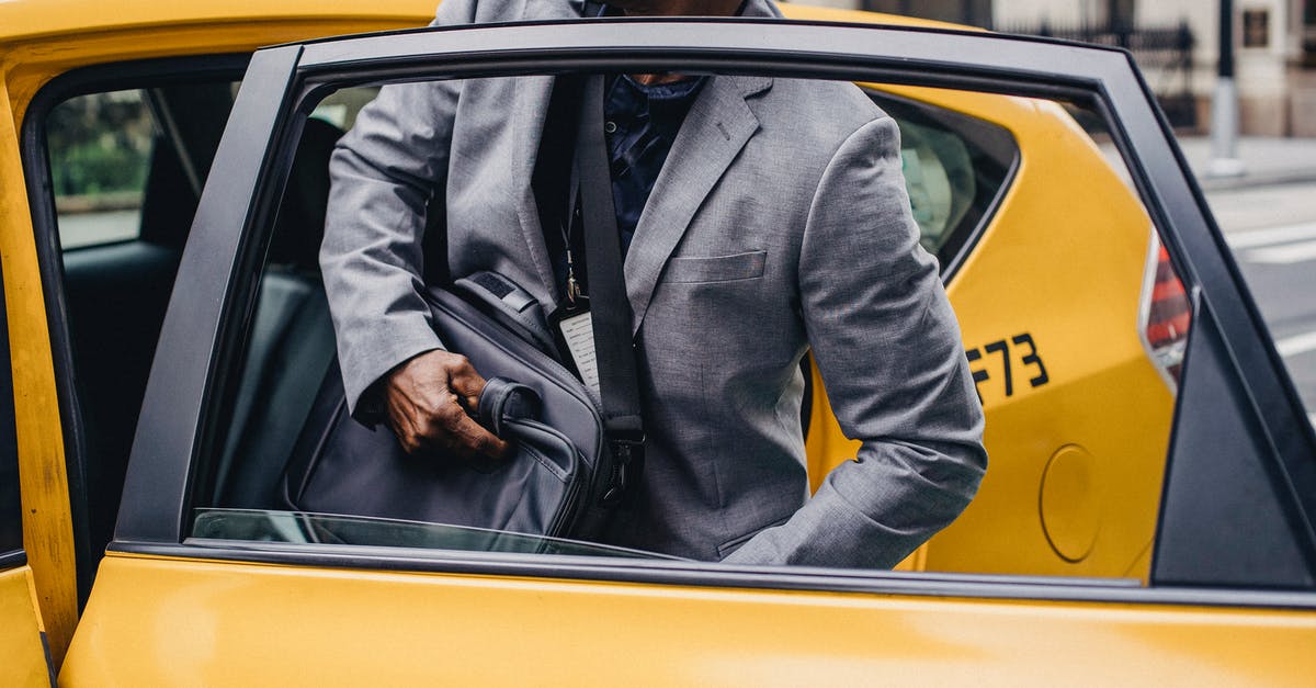 Amsterdam: parking a rental car downtown - Crop African American male in formal suit sitting in yellow taxi car parked on city street Amsterdam: parking a rental car downtown - Crop African American male in formal suit sitting in yellow taxi car parked on city street