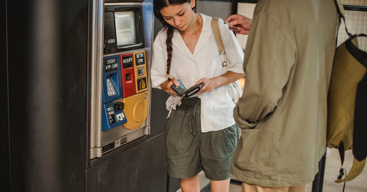 Amtrak - Why can she not buy two tickets for herself? - Calm young couple wearing casual clothes standing together near ticket vending machine with wallet in hands in underground Amtrak - Why can she not buy two tickets for herself? - Calm young couple wearing casual clothes standing together near ticket vending machine with wallet in hands in underground