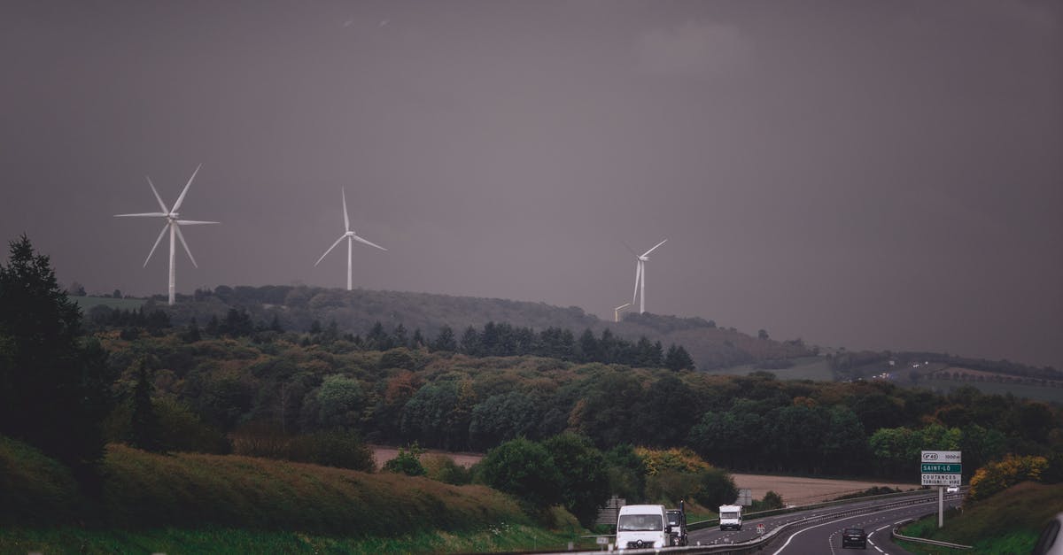 Any alternative ways to find hostels than hostelworld or hostelbookers [duplicate] - Asphalt highway running through grassy lush valley with modern wind turbine generators under gloomy overcast sky