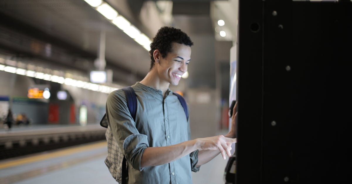 Any Maestro ATM in the US? - Joyful young African American male in casual clothes with backpack focusing and interacting with vending machine at underground station against blurred railway platform Any Maestro ATM in the US? - Joyful young African American male in casual clothes with backpack focusing and interacting with vending machine at underground station against blurred railway platform