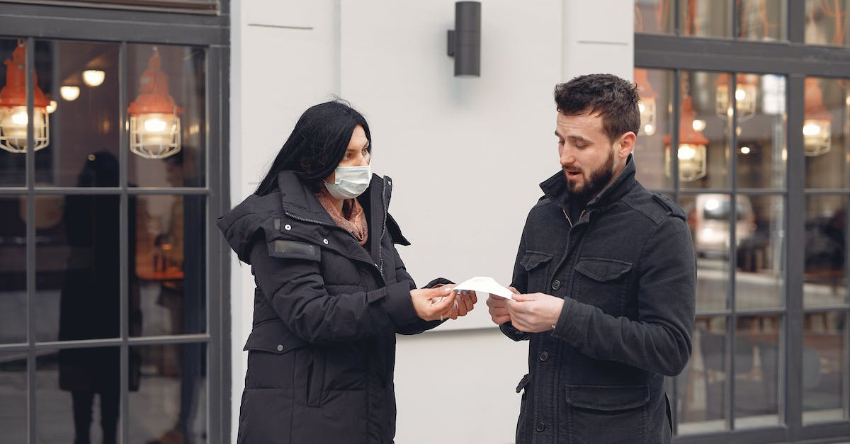 Any suggestions to ensure safety while hitchhiking? - Careful female volunteer in black down jacket suggesting protective facial mask for bearded male pedestrian on city street in cold season during coronavirus pandemic Any suggestions to ensure safety while hitchhiking? - Careful female volunteer in black down jacket suggesting protective facial mask for bearded male pedestrian on city street in cold season during coronavirus pandemic