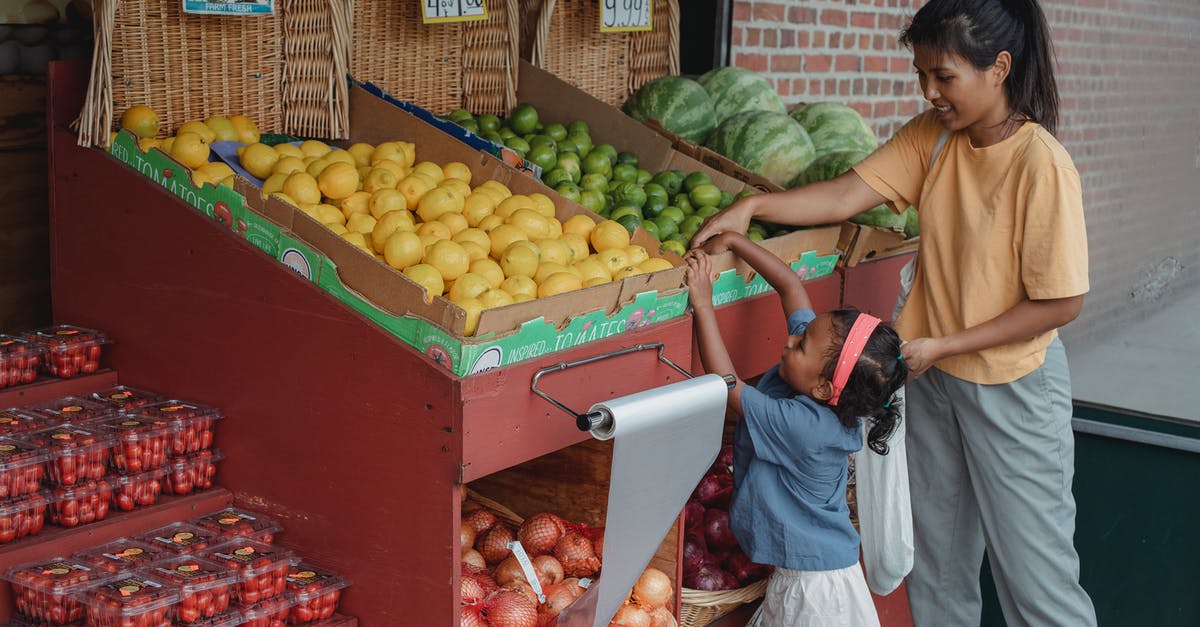 Apple Store in Ankara or Turkey - Small ethnic girl taking fruits from box with mother Apple Store in Ankara or Turkey - Small ethnic girl taking fruits from box with mother