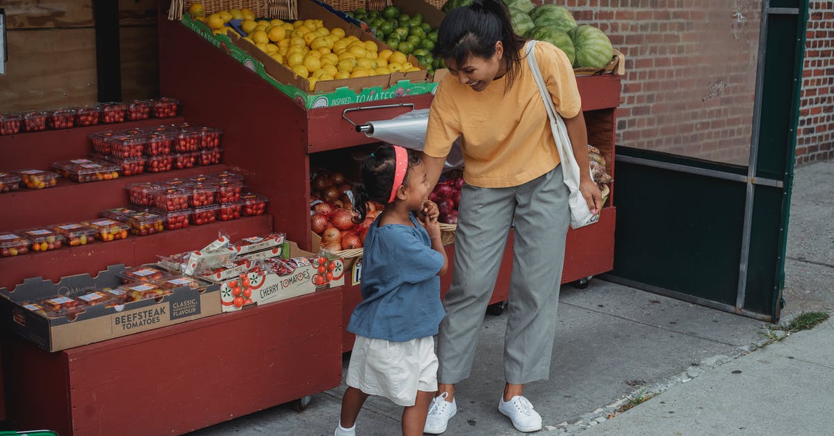 Apple Store in Ankara or Turkey - Cheerful ethnic woman with daughter at market with fruits Apple Store in Ankara or Turkey - Cheerful ethnic woman with daughter at market with fruits