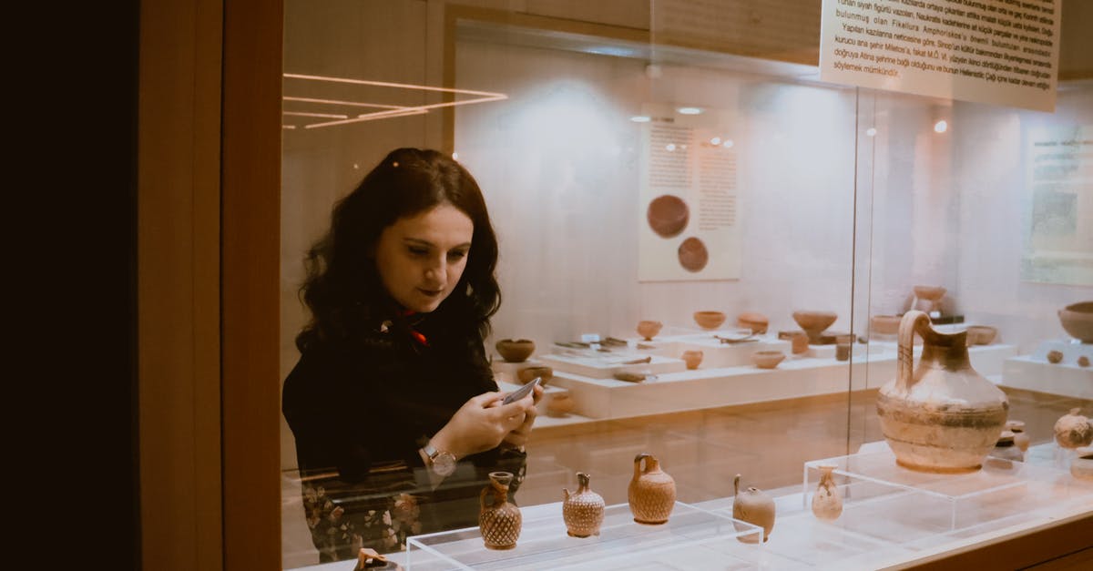 Applying again to visit UK, long term visit visa - Woman examining vases in exhibition hall Applying again to visit UK, long term visit visa - Woman examining vases in exhibition hall