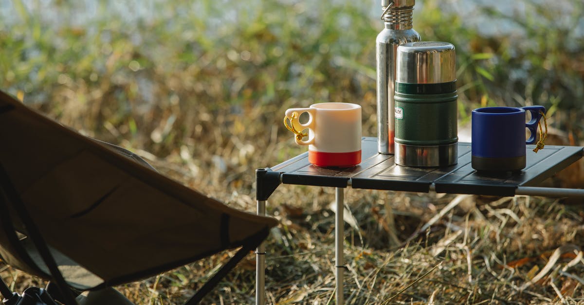 Applying for a UK visa when family members are traveling different portions of the trip - Stainless steel vacuum flasks and mugs with hot drinks on portable table near folding chair on grass shore Applying for a UK visa when family members are traveling different portions of the trip - Stainless steel vacuum flasks and mugs with hot drinks on portable table near folding chair on grass shore