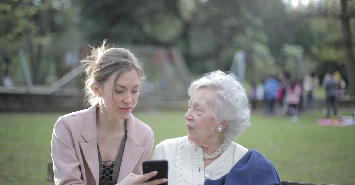 Applying for a visit visa for an elderly parent - Adult daughter teaching senior mother using smartphone in park Applying for a visit visa for an elderly parent - Adult daughter teaching senior mother using smartphone in park