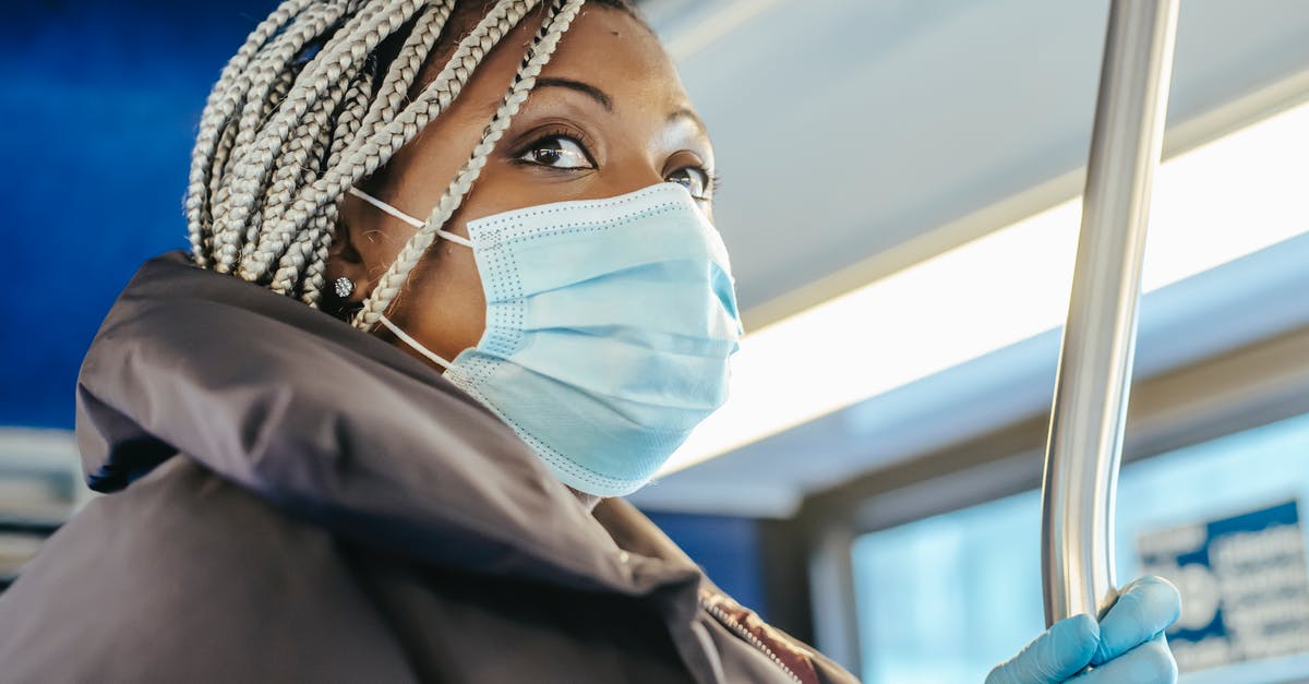 Are seatbelts unnecessary or unhelpful for safety for passengers in a bus? - Adult black woman in warm outfit and protective mask with gloves riding on public bus in daytime