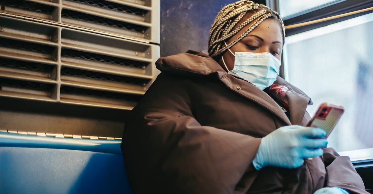 Are seatbelts unnecessary or unhelpful for safety for passengers in a bus? - African American woman with phone riding bus in pandemic