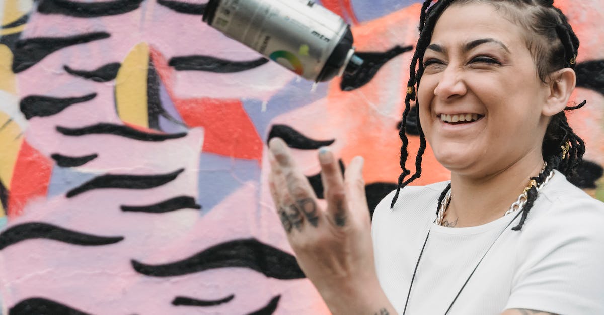 Are there any country- or city-specific dishes I can try whilst in Dakar, Senegal? - Happy ethnic female artist with braided hair tossing up spray paint can while standing near wall with creative graffiti on street