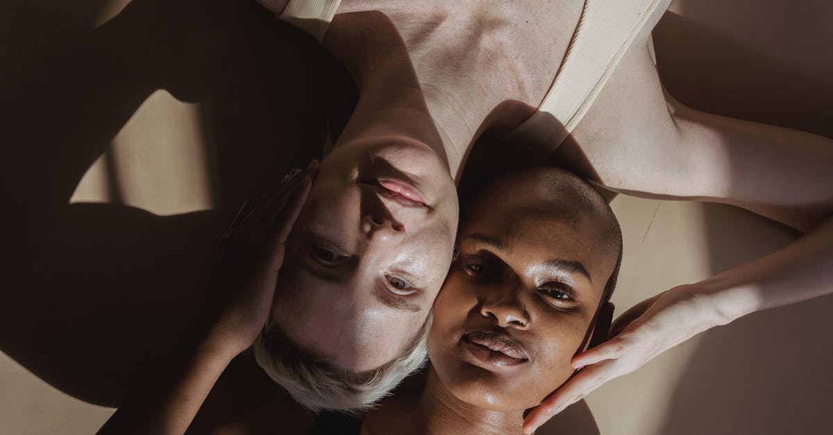 Are there cameras inside toilets in aeroplanes and in airports? [closed] - Top view of smiling multiethnic female models without makeup lying on gray surface and touching heads holding hands on face while looking at camera with shadows on face