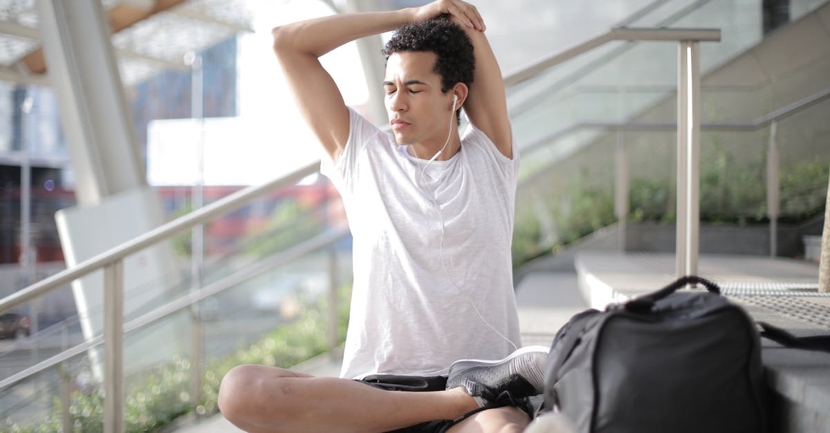 Are there certain countries that a black African traveler should avoid travelling to? [closed] - Young ethnic athlete in earbuds stretching body while sitting on stairs at entrance of contemporary building