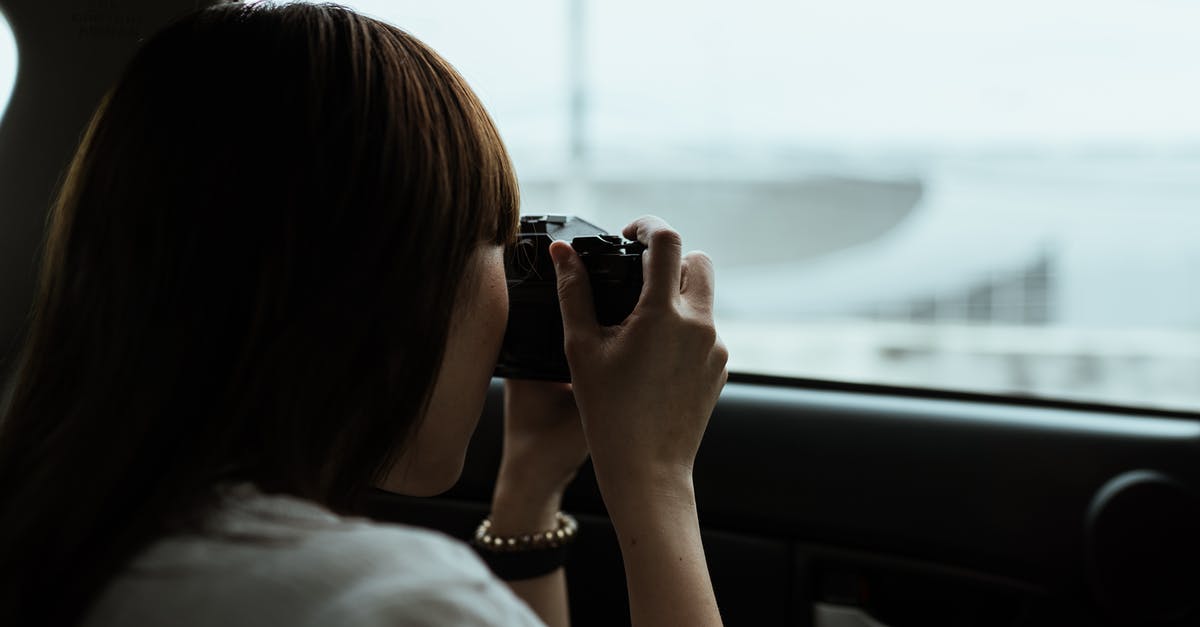 Are there issues with street photography in China when using a professional camera? - From behind anonymous brunette in white shirt taking pictures of urban buildings while riding in car passenger seat on daytime Are there issues with street photography in China when using a professional camera? - From behind anonymous brunette in white shirt taking pictures of urban buildings while riding in car passenger seat on daytime