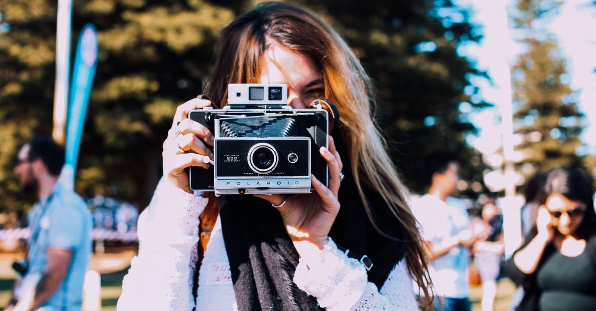 Are there issues with street photography in China when using a professional camera? - Young female photographer in casual outfit taking pictures on retro photo camera while standing in crowded sunny park Are there issues with street photography in China when using a professional camera? - Young female photographer in casual outfit taking pictures on retro photo camera while standing in crowded sunny park