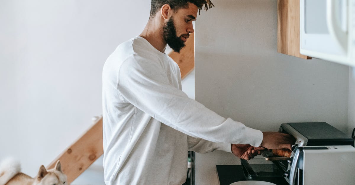 Are there microwaves to heat baby food at Brussels airport? - Bearded young black man heating croissant in microwave oven standing near dog