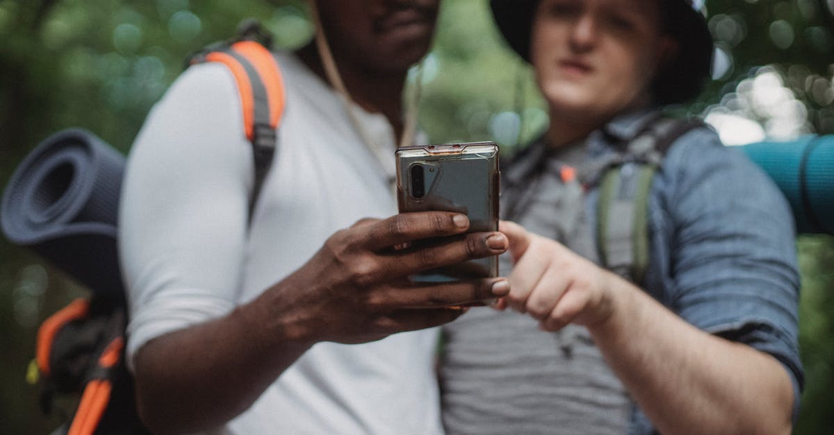 Are there online resources which shows tourism statistics of a country? - Crop young multiracial male backpackers browsing internet on cellphone while spending time together on weekend in park Are there online resources which shows tourism statistics of a country? - Crop young multiracial male backpackers browsing internet on cellphone while spending time together on weekend in park