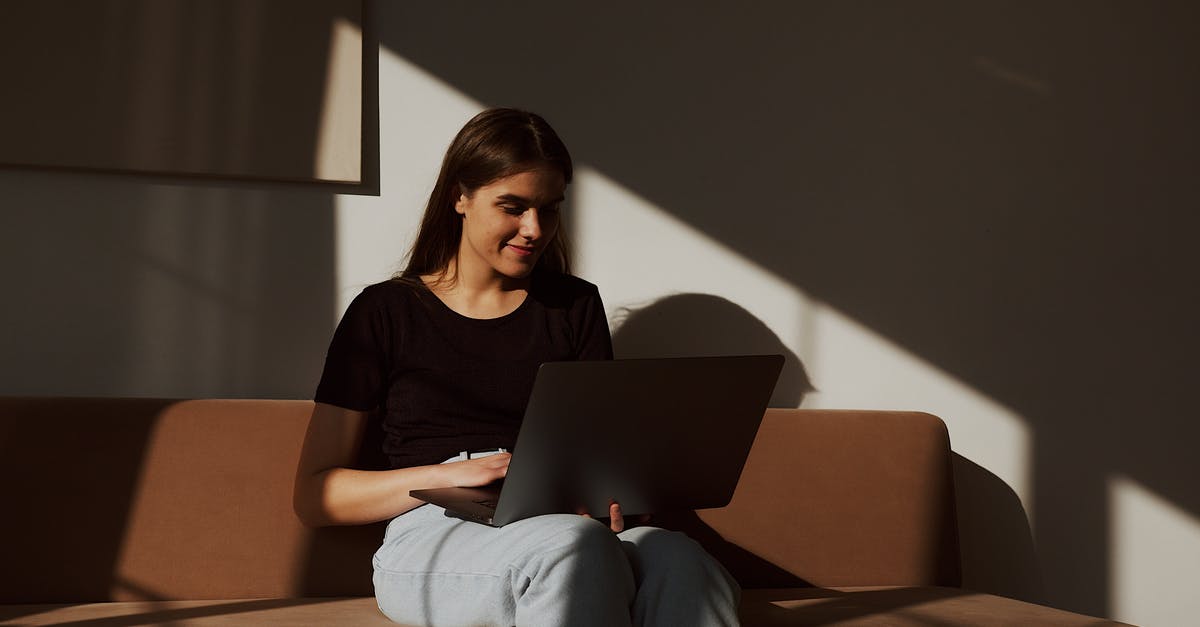 Are there some places I can stay for free in South Korea besides couch surfing? - Positive smiling young lady wearing casual clothes sitting on comfy sofa and browsing netbook in shadows light in cozy living room