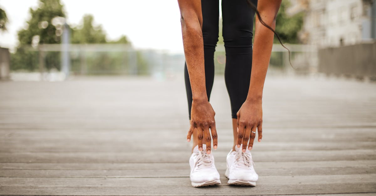 Are Trinidad and Tobago as well as Suriname safe places to travel alone? - From below crop slender female athlete in sportswear and white sneakers doing standing forward bend exercise for stretching body on wooden floor of street sports ground against blurred urban environment in daytime