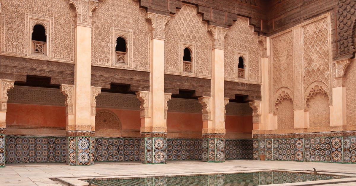 As a Moroccan citizen travelling from Budapest to Morocco with a layover in UK for 8 hours do I need a visa to transit? [duplicate] - Main courtyard of ancient Ben Youssef Madrasa with arched passage and walls decorated with arabesque ornaments on sunny day in Marrakesh
