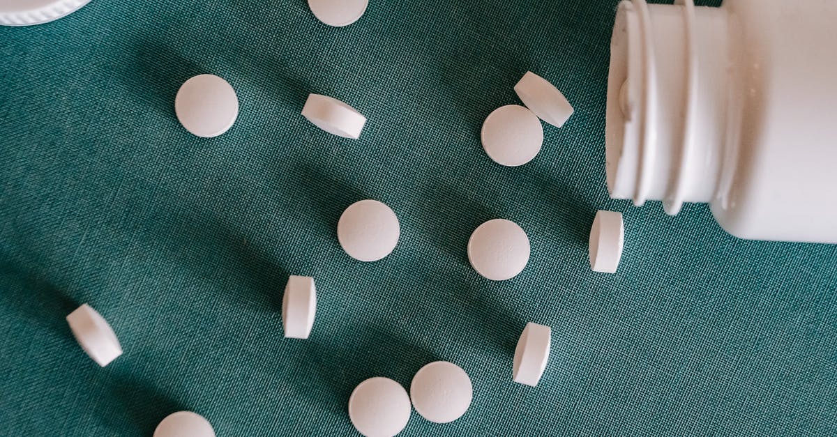 As a tourist in the EU, can you order prescription drugs from your home country? [closed] - Top view of similar small round white pills spilled from plastic container on green surface