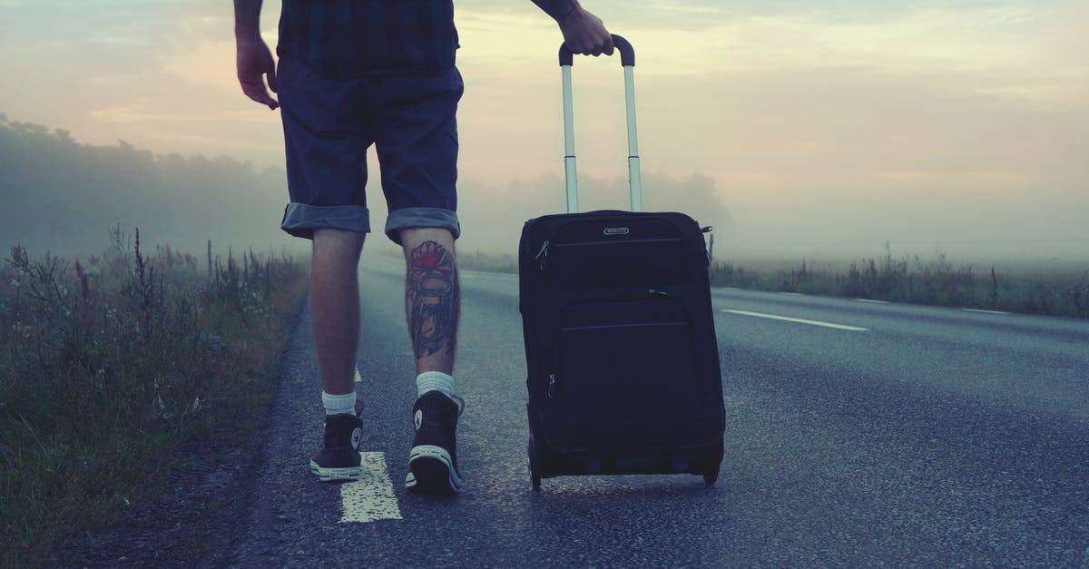 Assuring luggage isn't lost with short layover - Man Walking on the Road Holding Black Luggage during Sunset