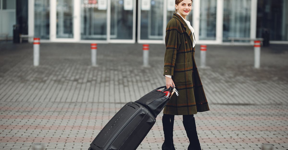 Atlanta Terminal Change: Domestic to International with Bags - Full length of smiling female manager in stylish coat walking with suitcase and bag while traveling on business trip smiling away