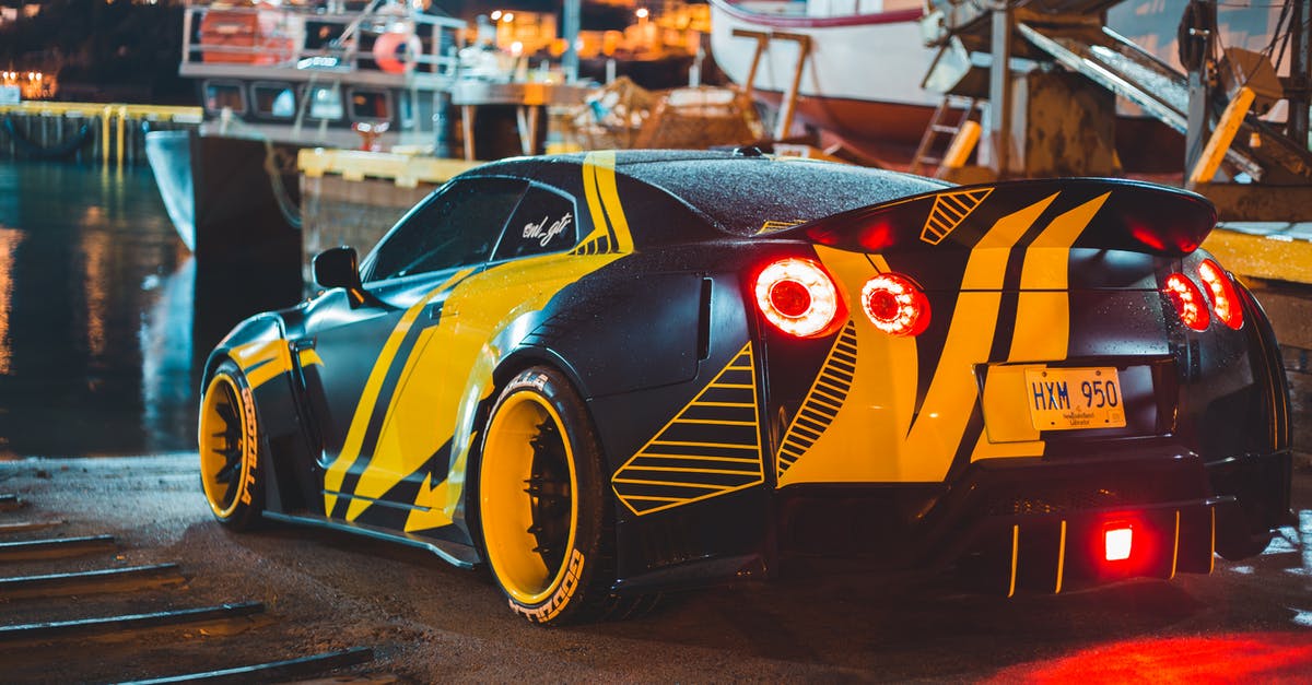 Australian with P2 license hiring car in Spain - Contemporary sports car with glowing taillights near river with ships in city harbor in evening Australian with P2 license hiring car in Spain - Contemporary sports car with glowing taillights near river with ships in city harbor in evening