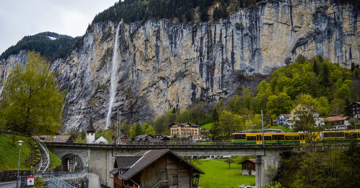 Avoiding tilting trains in Switzerland - Train riding in mountainous countryside near waterfall flowing through rocky cliff Avoiding tilting trains in Switzerland - Train riding in mountainous countryside near waterfall flowing through rocky cliff