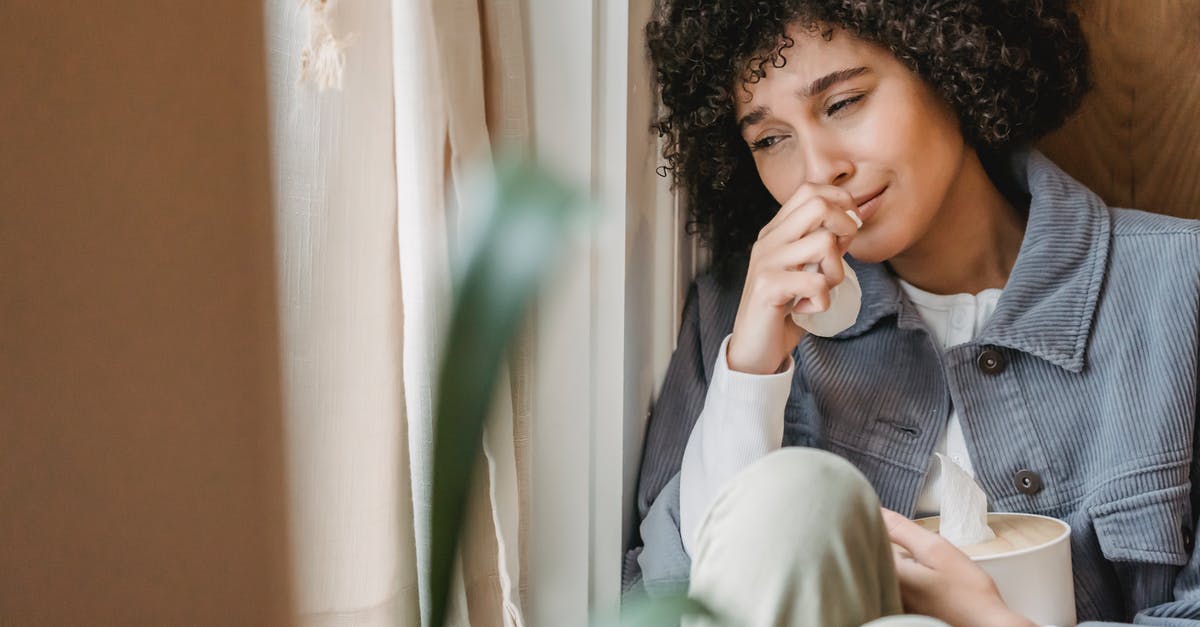 Bad hostel, recourse? - Sad African American female with tissue sitting on windowsill and crying while suffering from sorrow Bad hostel, recourse? - Sad African American female with tissue sitting on windowsill and crying while suffering from sorrow