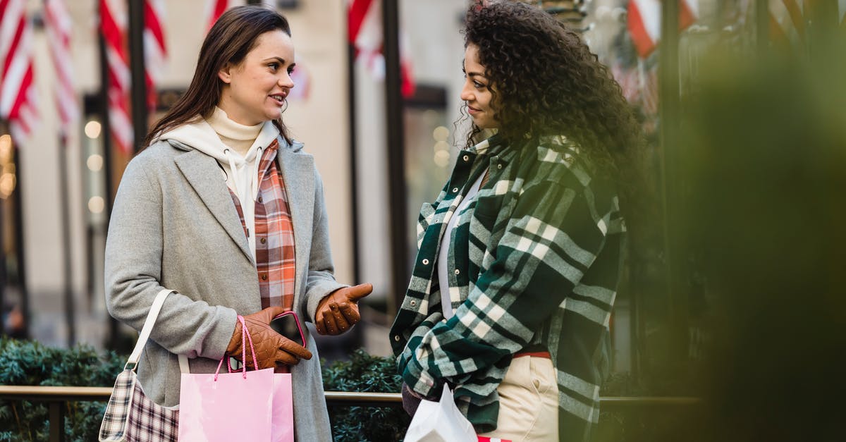 Bag wrapping at airports in USA - Positive young multiracial women chatting on street after shopping Bag wrapping at airports in USA - Positive young multiracial women chatting on street after shopping