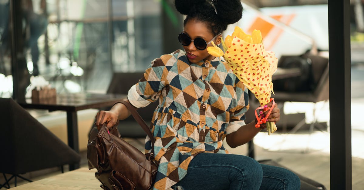 Bag wrapping at airports in USA - Photograph of Woman Seating on Table Holding Bouquet of Flowers Bag wrapping at airports in USA - Photograph of Woman Seating on Table Holding Bouquet of Flowers