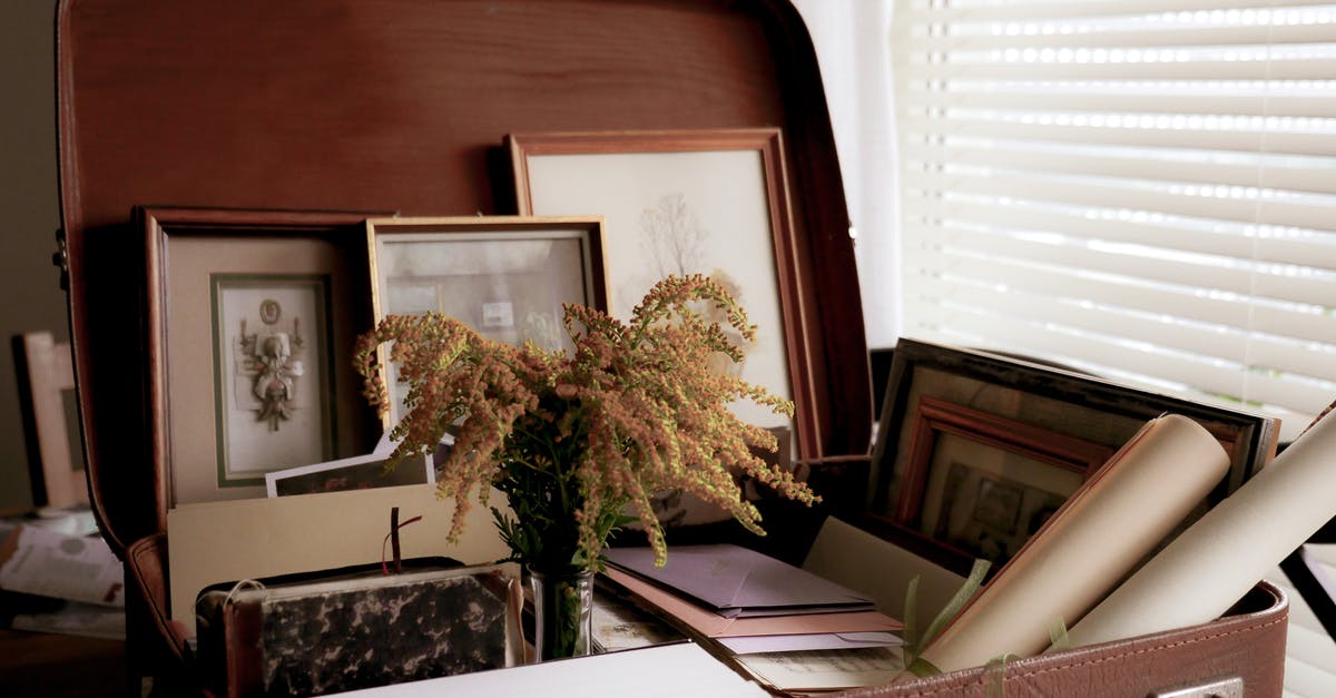 Baggage and check-ins on different airlines - Papers and flowers placed in vintage suitcase on table near window with curtain and window blind Baggage and check-ins on different airlines - Papers and flowers placed in vintage suitcase on table near window with curtain and window blind