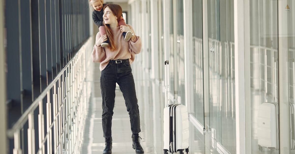 Being separated from one's young children on a flight - Cheerful woman with daughter and suitcase in airport Being separated from one's young children on a flight - Cheerful woman with daughter and suitcase in airport