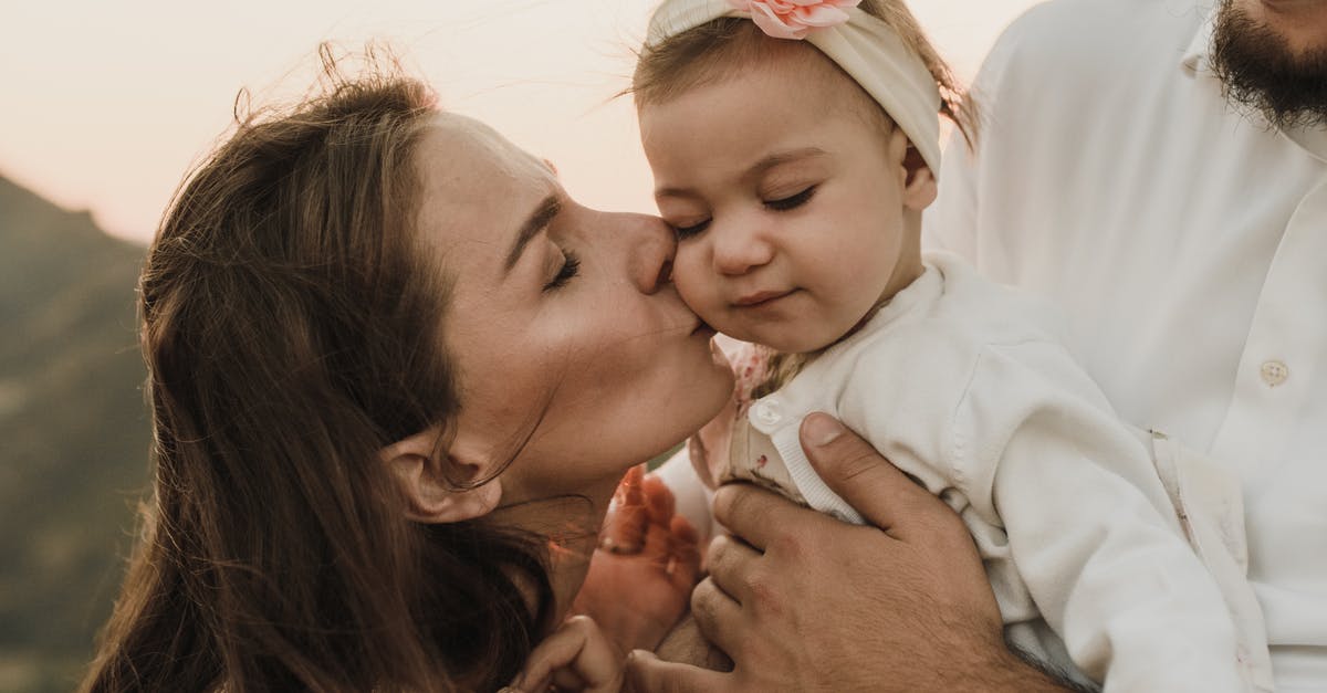 Belize with two small children [closed] - Loving mother kissing cute baby daughter held by crop father while having family day in nature