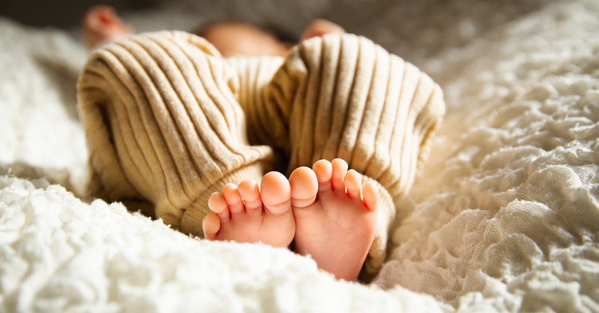 Below standard baby crib - Anonymous barefooted baby sleeping on soft bed in sunlight Below standard baby crib - Anonymous barefooted baby sleeping on soft bed in sunlight