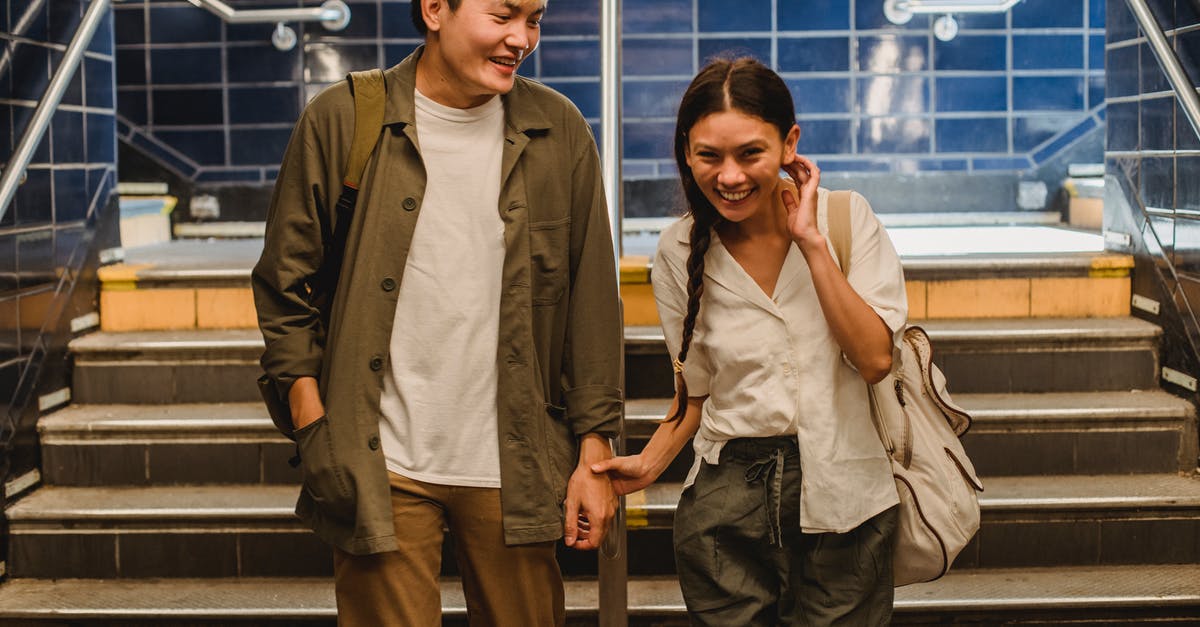 Best Rail Pass for Italy - Happy Asian couple in casual clothes holding hands and walking together in underground hallway Best Rail Pass for Italy - Happy Asian couple in casual clothes holding hands and walking together in underground hallway