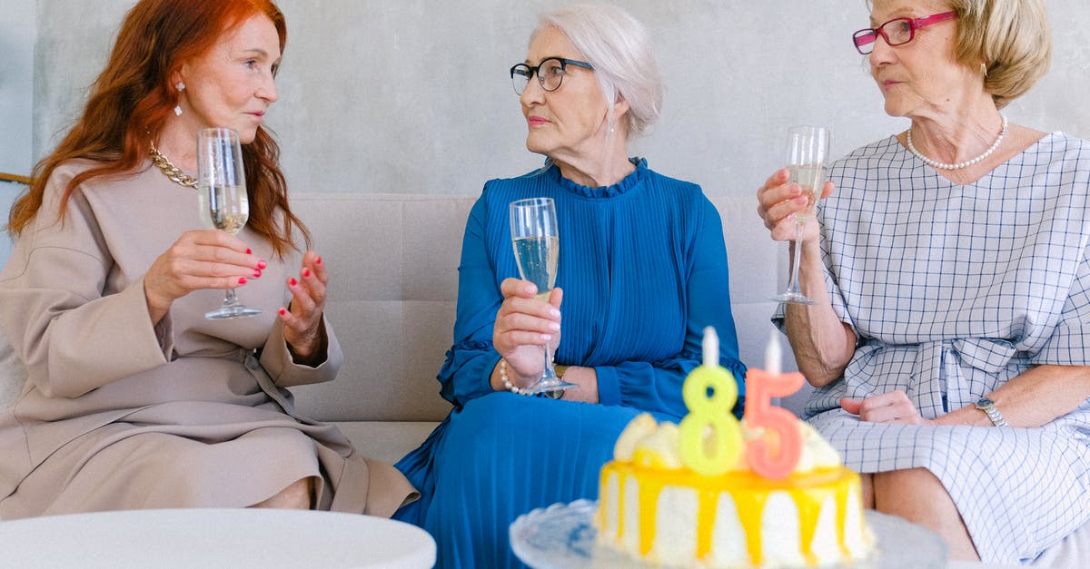 Best visa for the UK if buying a holiday home - Aged best friends with glasses of champagne talking at table with birthday cake decorated with candles Best visa for the UK if buying a holiday home - Aged best friends with glasses of champagne talking at table with birthday cake decorated with candles